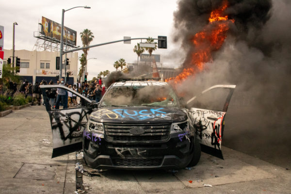 A police cruiser—once a symbol of authority—now stands gutted, its insides consumed by fire and its exterior marked by the rage of a people unheard. This is not mindless destruction—it’s an indictment. Every word sprayed on the metal, every flame licking the sky, reflects a generation pushed past its limits. This moment captures the boiling point of centuries of state violence and the reclaiming of public power.